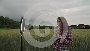 Blogger recording video at wheat field. Using ring lamp and smartphone outdoor