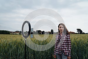 Blogger recording video at wheat field. Using ring lamp and smartphone outdoor