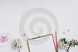 Blogger`s workplace: a tablet with a clip and a sheet of white paper, a pencil and apple flowers on a white background with copy