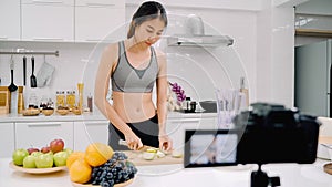 Blogger sporty Asian woman using camera recording how to make apple juice video for her subscriber, female use organic fruit