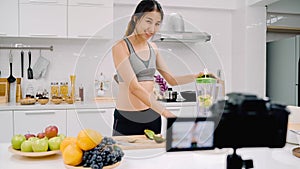 Blogger sporty Asian woman using camera recording how to make apple juice video for her subscriber, female use organic fruit