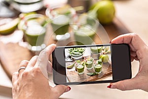 Blogger woman making photo of smoothie with cell phone