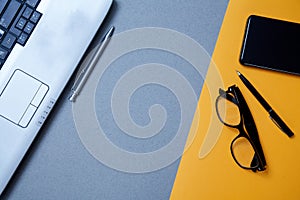 Blogging, blog and blogger or social media concept: a laptop, glasses and an external hard drive on a grey and yellow background.