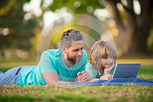 Blogging. Happy father using laptop relax with schooler son holding laptop. Childhood and parenthood kids concept. Video