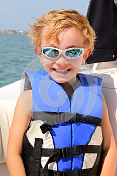Blond 6yr old child with life jacket & sun glasses