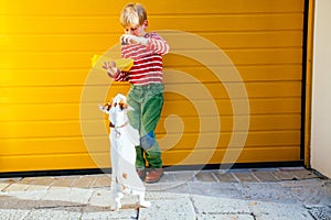 Blond baby boy with lunch box with some food playing, training with his dog