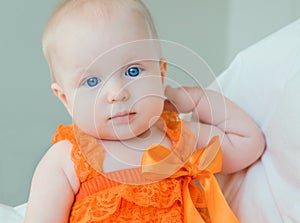 Blond baby girl with blue eyes in a romper