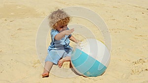 A blond boy 2 years old plays on the beach with boll on a Sunny summer day.4K