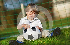 Blond boy of 3 playing soccer with football on football field