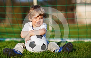 Blond boy of 3 playing soccer with football on football field