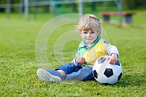 Blond boy of 3 playing soccer with football on football field