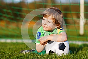 Blond boy of 4 playing soccer with football on football field