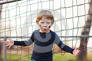 Blond boy of 4 playing soccer with football on football field