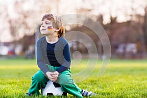 Blond boy of 4 playing soccer with football on football field