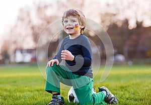 Blond boy of 4 playing soccer with football on football field