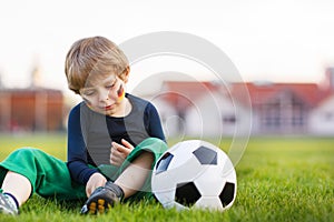 Blond boy of 4 playing soccer with football on football field