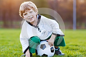 Blond boy of 4 playing soccer with football on football field