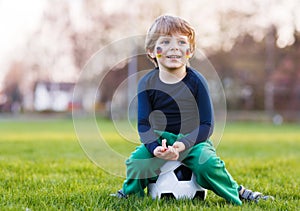 Blond boy of 4 playing soccer with football on football field