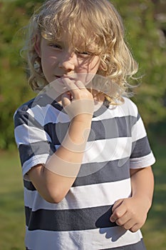 The blond boy is biting his nails.