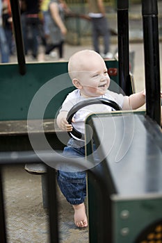 Blond boy driving a toy car