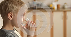 Blond boy enjoys drinking water from the glass and shows the class. Smiling boy quenches his thirst.