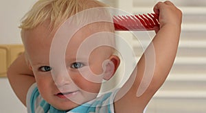 Blond boy is learning to comb himself