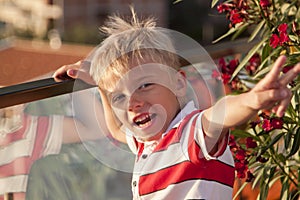 blond boy looks at camera and throws his hand up with a vict