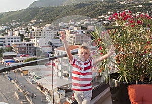 blond boy looks at the camera and throws his hand up with a vict