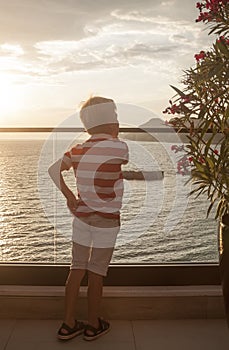 blond boy looks thoughtfully into the distance at the sea standi