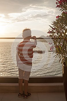 blond boy looks thoughtfully into the distance at the sea standi