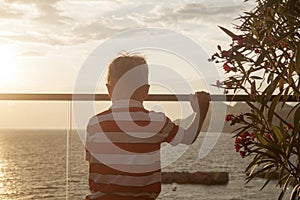 blond boy looks thoughtfully into the distance at the sea standi