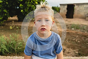 Blond boy making funny faces outdoors