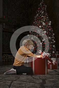 Blond boy open Christmas present. Surprised and joyful baby with great Xmas presents. Vertical frame