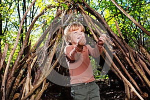 Blond boy play with soap bubbles in park hut of branches