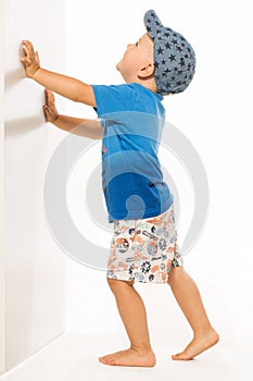 Blond boy pushing he wall white bacground