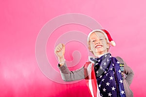 Blond boy with santa hat, American flag and raised fist in victory sign