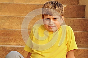 Blond boy sitting on stairs at sunset