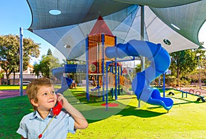 Blond boy speaks on red telephone