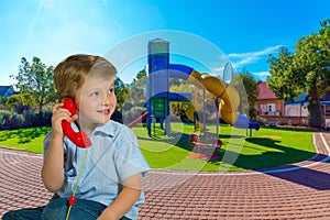 Blond boy speaks on a red telephone