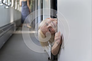 Blond boy in train carriage looks out of compartment. Little child in train on family vacation