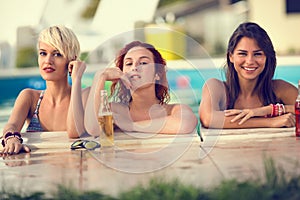 Blond, brunette and red haired female bathers posing on edge of