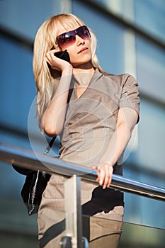 Fashion blond woman in sunglasses calling on mobile phone