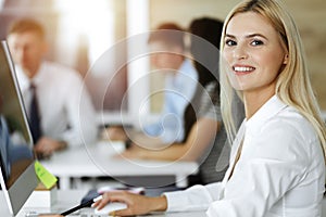 Blond business woman using computer at workplace in sunny office. Working for pleasure and success