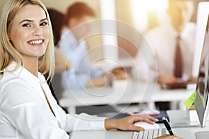 Blond business woman using computer at workplace in sunny office. Working for pleasure and success