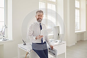 Blond businessman with papers documents in hands standing working in office