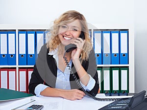 Blond businesswoman at office speaking with client at phone