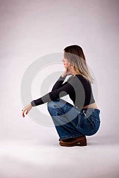 Blond casual girl crouching blue jeans