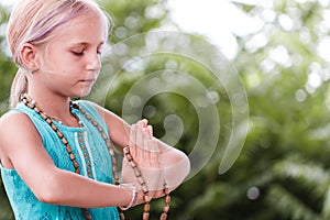 Blond caucasian girl in namaste. girl hands in namaste gesture outdoor summer day. yoga, mindfulness, harmony concept - girl