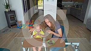 Blond child and caucasian woman eating cherry berry sitting by glass table