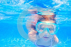 Blond child girl underwater swimming in pool
